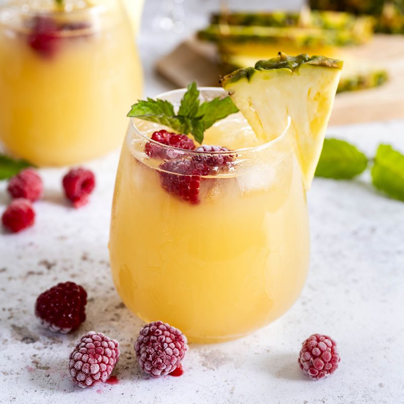 Exotic Trilogy cocktail with pineapple & raspberry garnish