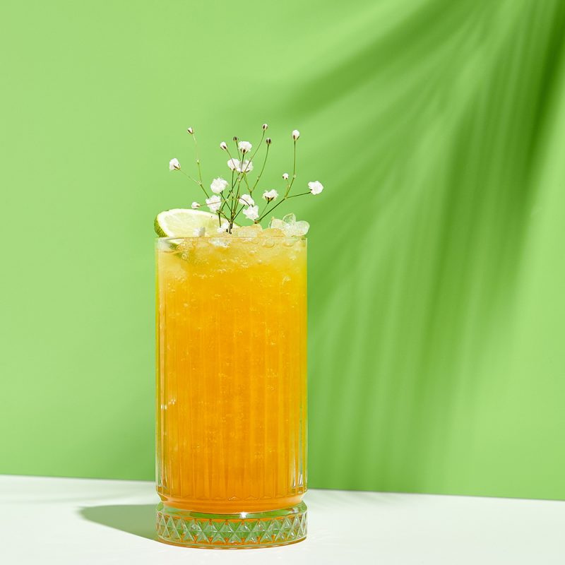Spicy mango-maple cocktail with lime & flower garnish